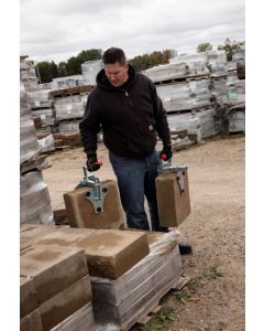 A worker using paver clamps to carry large thick pavers